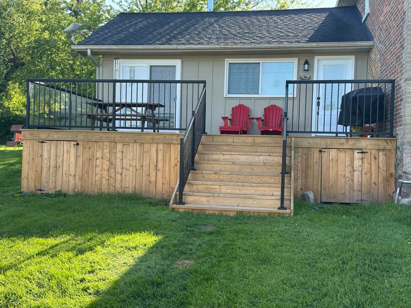 Backyard cedar deck with railing and Muskoka chairs by AEG Home Improvements