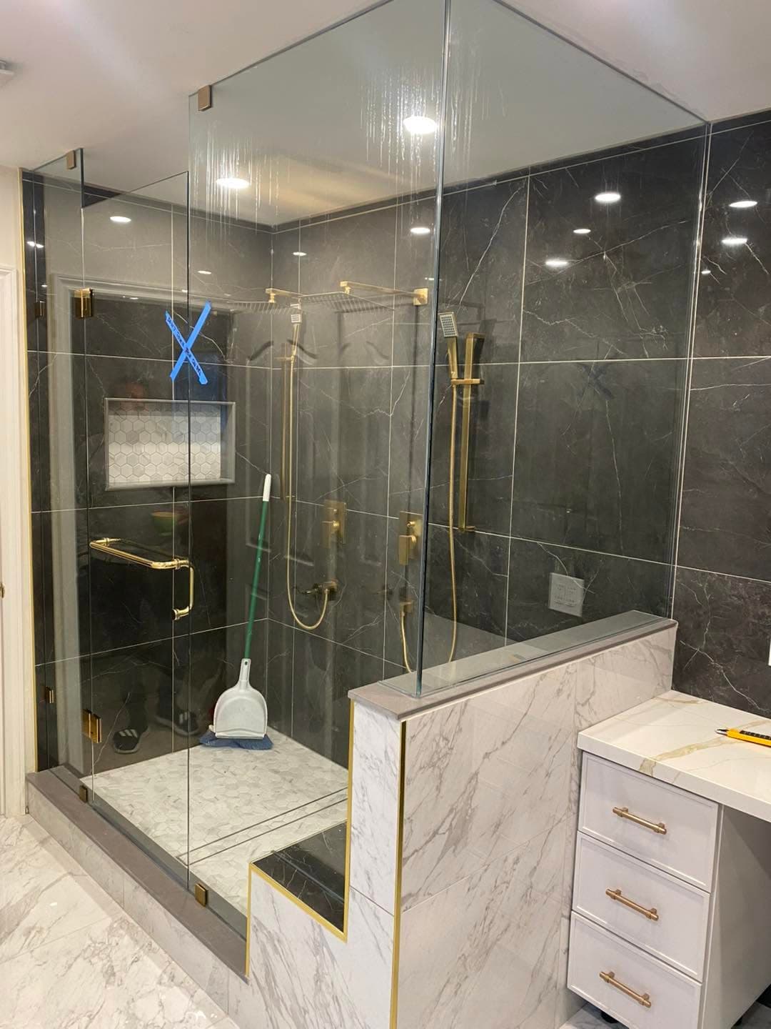 Custom tiled glass shower with gold fixtures by AEG Home Improvements