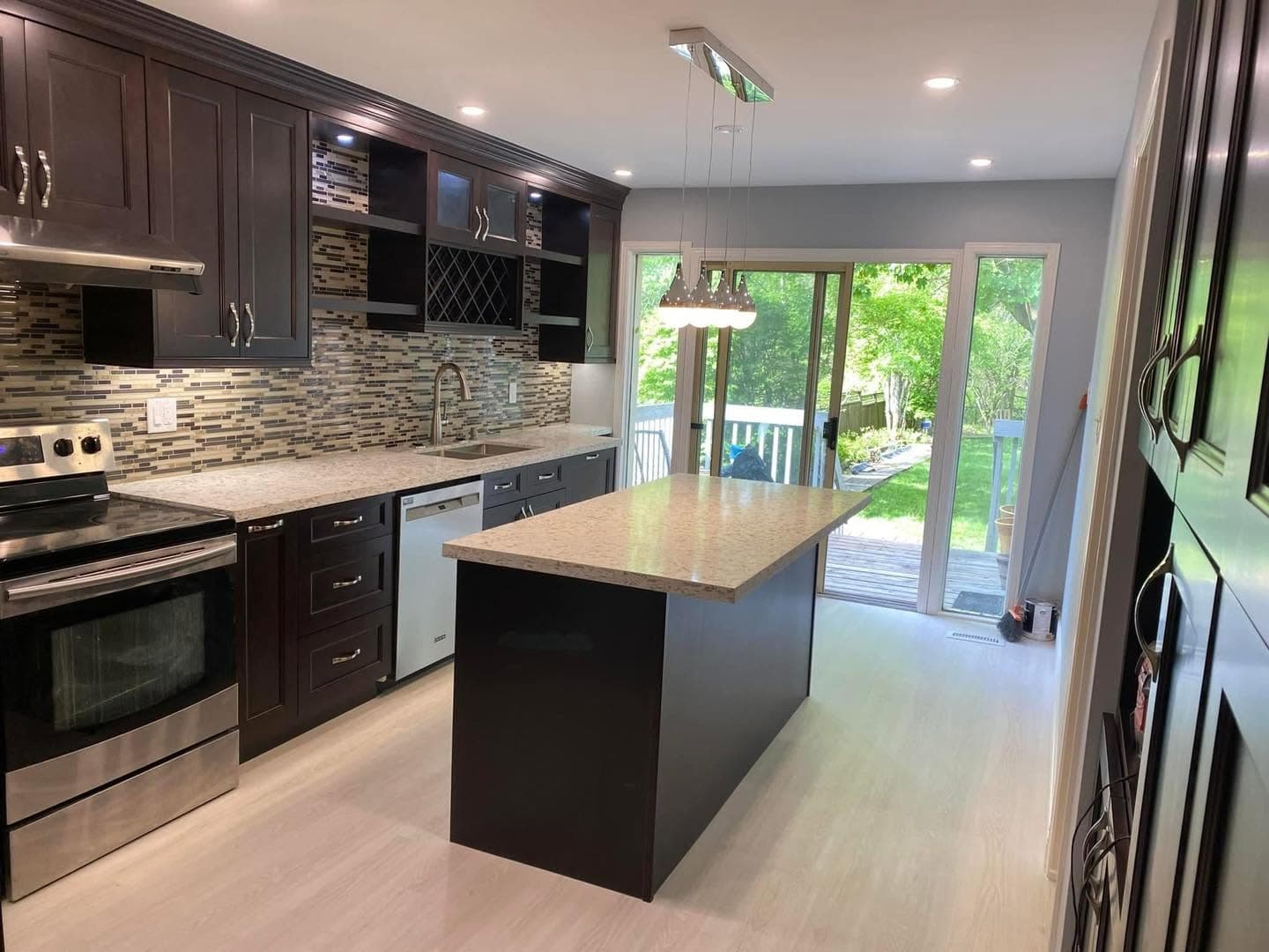 Renovated kitchen with dark cabinetry and island by AEG Home Improvements