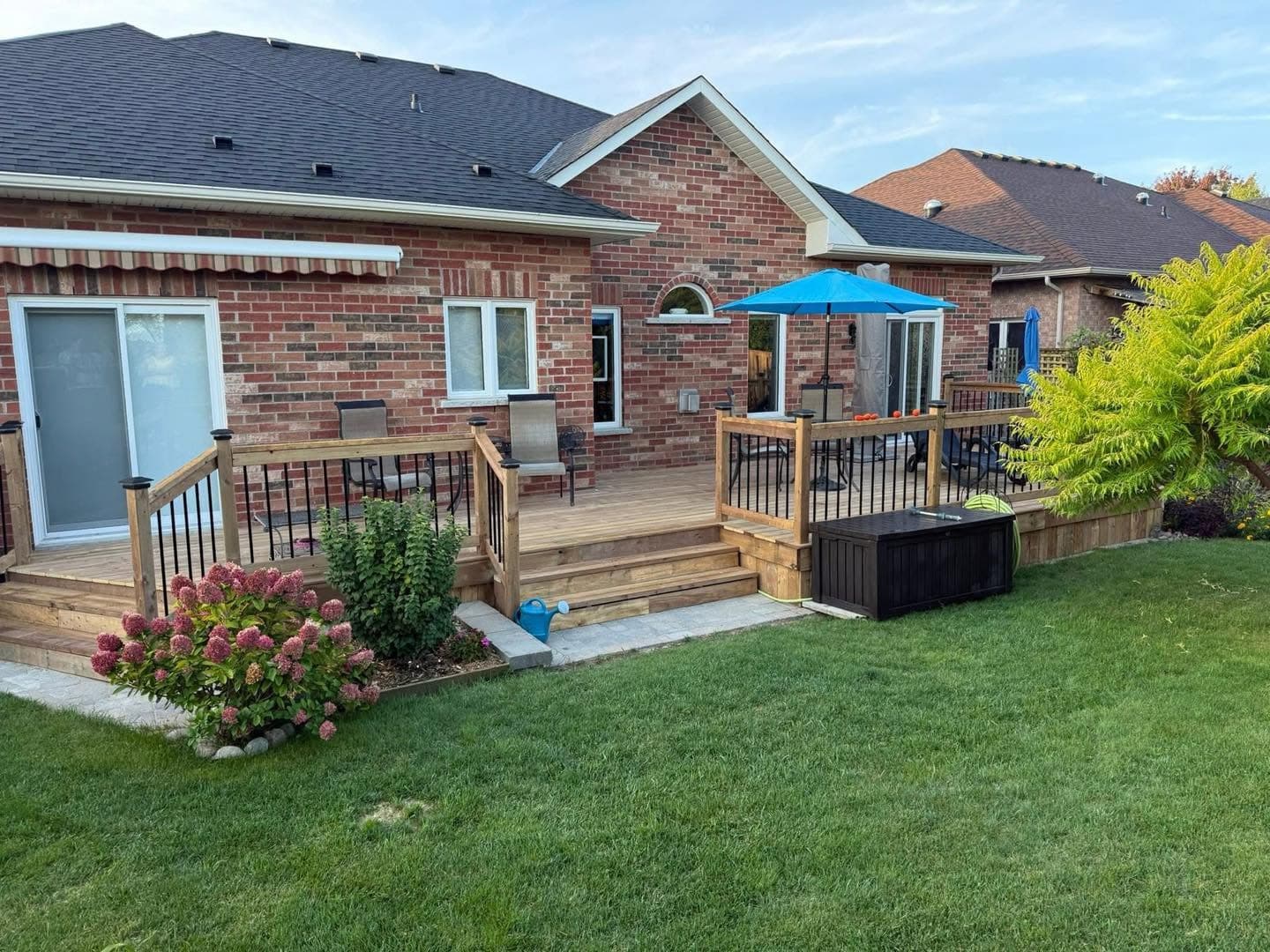 Backyard deck attached to a brick home with landscaped yard